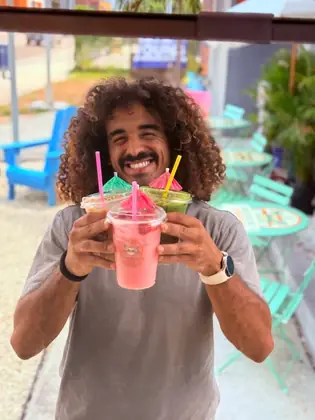 Smiling customer holding three colorful BrewKini’s drinks
